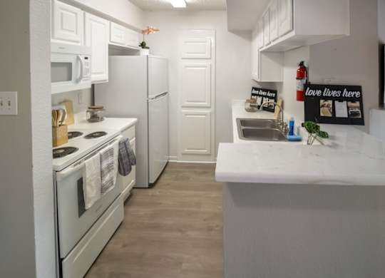 a kitchen with white appliances and white cabinets in a home at Pine Creek