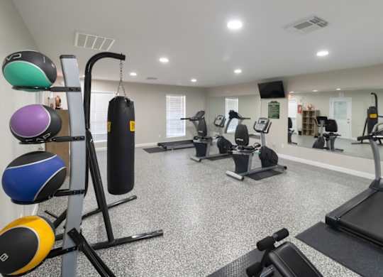 A gym with cardio equipment and weights at The Forest Apartments in Houston, TX