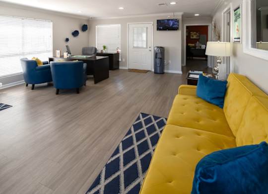 the welcoming office with a bright yellow couch at Kirkwood Landing Apartments