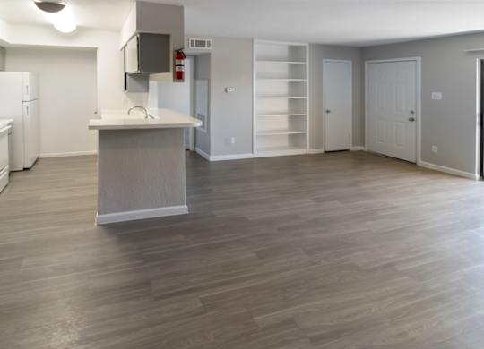 a large living room and kitchen with neutral paint and gray cabinets and white appliances and shelving