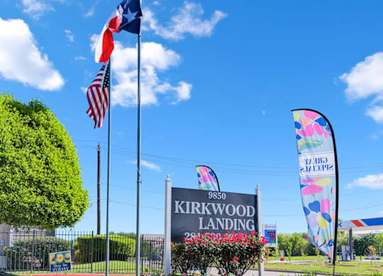 the entrance to kirkwood landing with flags and a sign