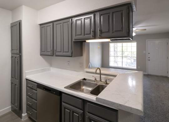 a kitchen with dark gray cabinets and white counter tops and a stainless steel sink