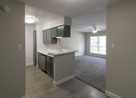 a spacious kitchen with stainless steel appliances and living room with a ceiling fan