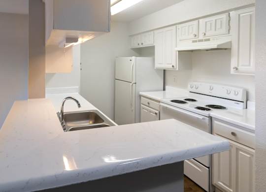 a kitchen with white appliances, white cabinets, and white counter tops
