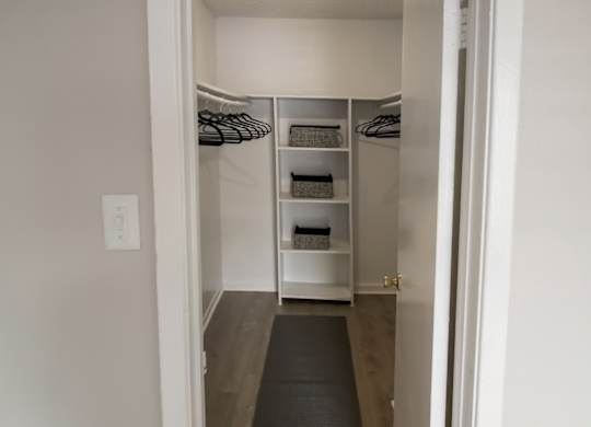 a walk in closet with shelves and hanging bars