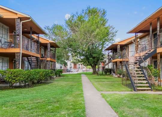 the lush green area with a large tree between two residential buildings at The Forest Apartments