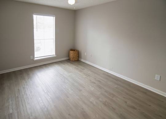 a spacious Pine Creek bedroom with a large window and illuminated ceiling fan