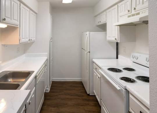 a kitchen with white appliances, white cabinets, and wood-style flooring