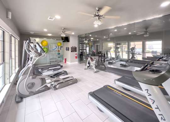 a gym with treadmills and other exercise equipment at Crosby at Westchase apartments in houston, tx
