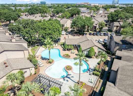 A bird's eye view of a residential area with a swimming pool and palm trees.