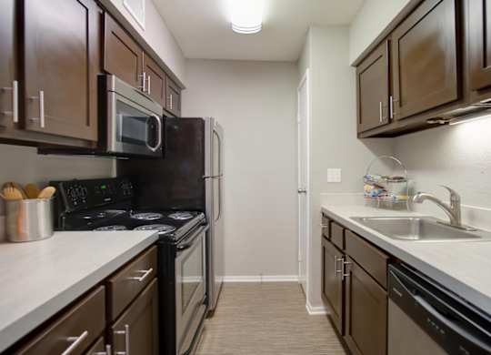 a kitchen with stainless steel appliances, built-in microwave, and wood cabinets at Hudson at Westchase