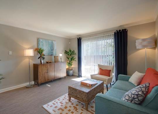 a spacious living room with modern features, model furnishings, and a sliding glass door
