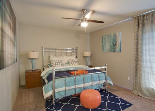 a bedroom with a bed and an illuminated ceiling fan, and large window behind a curtain