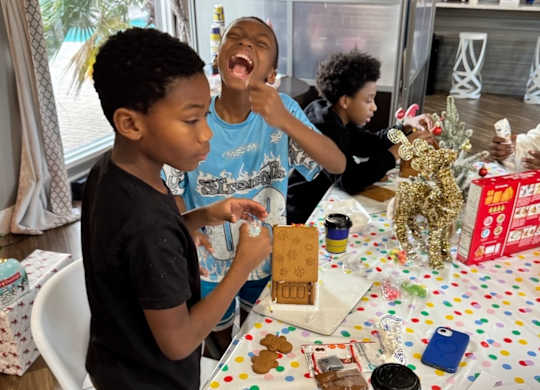 Three boys are playing with a toy set on a table.