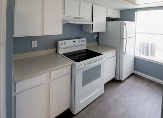 a spacious kitchen with white cabinets and appliances and a window at Winford Place