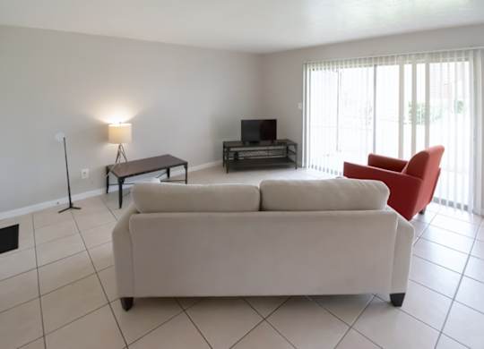 a tiled living room with sliding glass doors and model furnishings