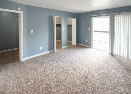 A spacious bedroom with large closets, sliding glass doors to a deck and carpet at Winford Place