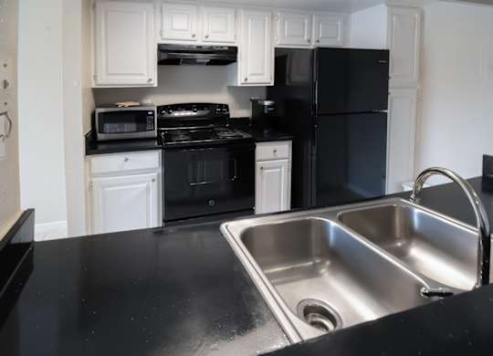 a kitchen with sleek black appliances, a stainless steel link, and white cabinets