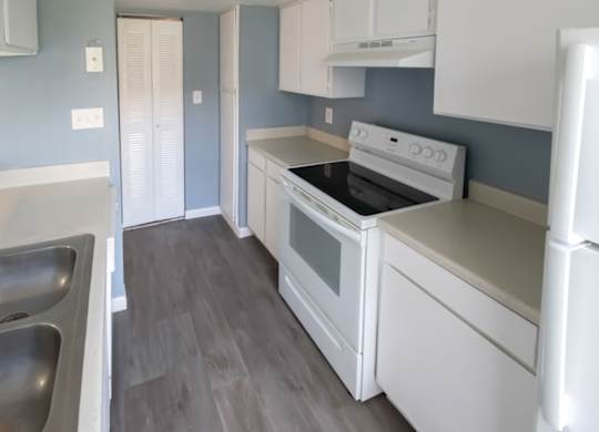 a kitchen with white appliances and a double stainless steel sink