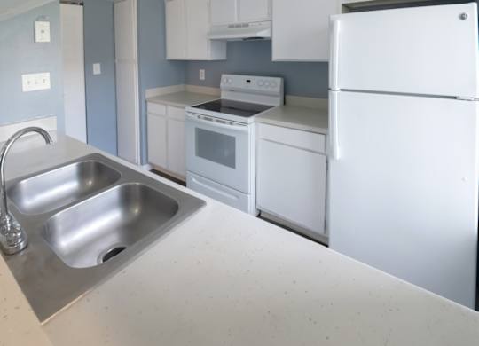 a kitchen with white appliances and cabinets and a stainless steel double sink