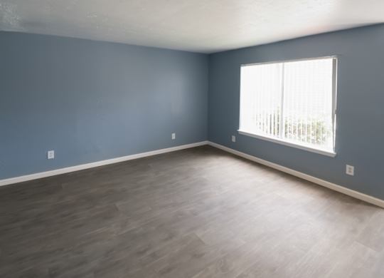 a large room with a big window and wood-style flooring in a Winford Place home