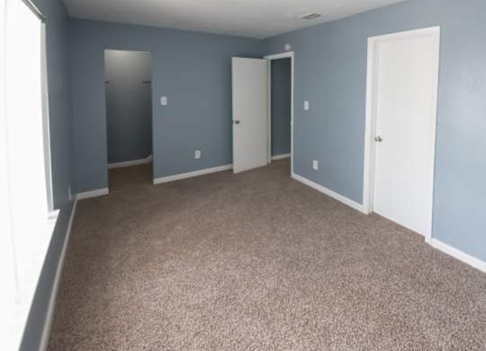 a blue carpeted bedroom with a large closet