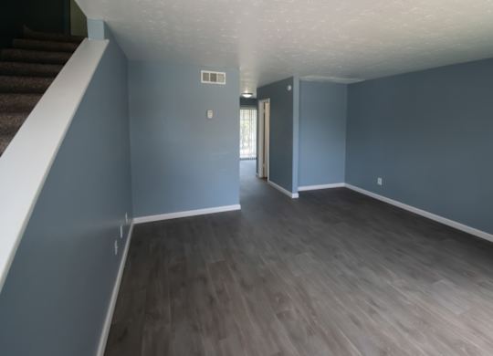 a renovated living room with wood-style flooring and blue-gray walls at Winford Place