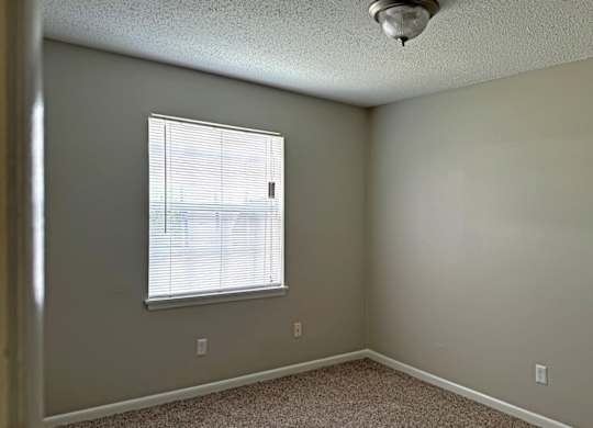 an empty bedroom with a window and a ceiling fan at Spring Lake Cove Apartments, Alabama