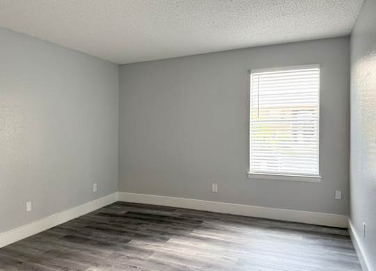 an empty room with wood floors and a window at Ascot Place Apartments, Birmingham
