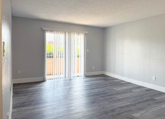 an empty living room with wood floors and a sliding glass door at Ascot Place Apartments, Birmingham, AL