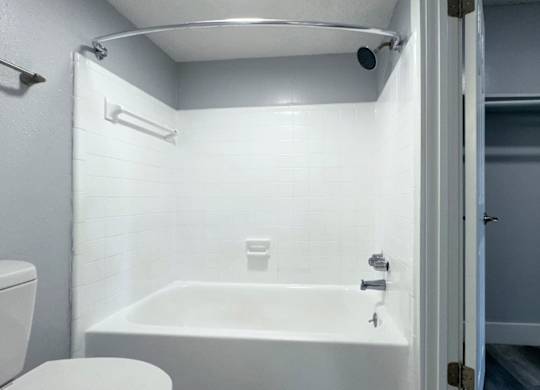 a white bathroom with a tub and a toilet at Ascot Place Apartments, Alabama