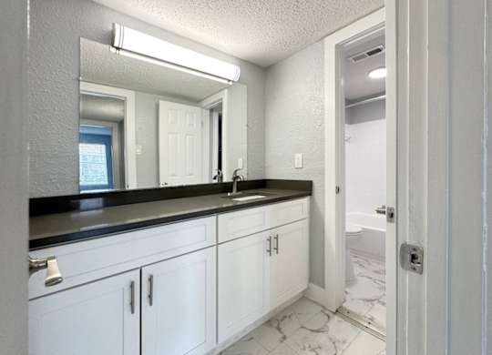 a bathroom with white cabinets and a sink and a mirror at Ascot Place Apartments, Birmingham, AL 35235