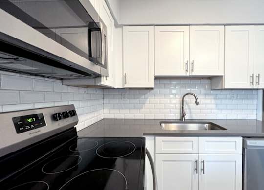 a white kitchen with black appliances and white cabinets at Ascot Place Apartments, Birmingham, AL 35235