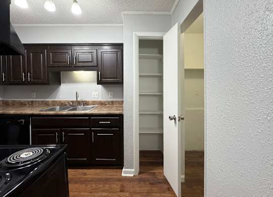 a kitchen with dark cabinets and a sink and an open doorway at Ascot Place Apartments, Birmingham