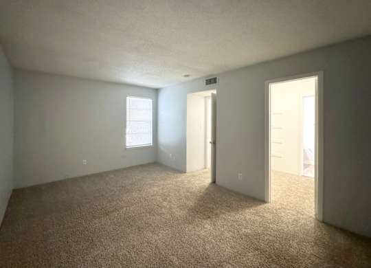 a large primary bedroom with carpet and a door to a bedroom at Ascot Place Apartments, Birmingham, AL
