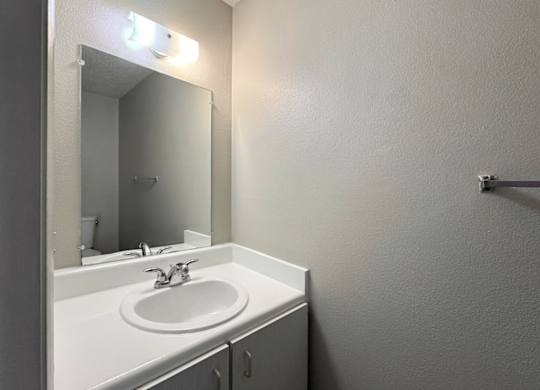 A white sink in a bathroom with a mirror above it.