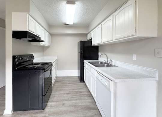 A kitchen with black appliances and white cabinets.