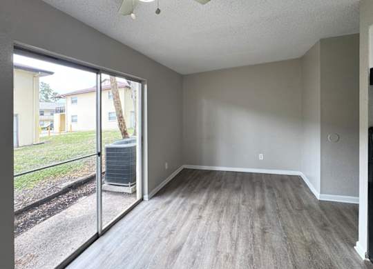 A room with a sliding glass door leading to a backyard.