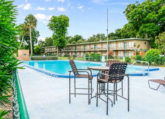 A poolside table with chairs is set up next to the Park Apartments swimming pool in Daytona Beach, FL.