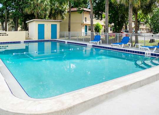 a large swimming pool with blue chairs around it