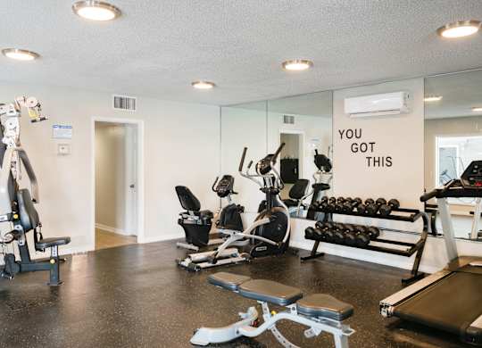 a home gym with weights and cardio equipment and a sign that says you got this