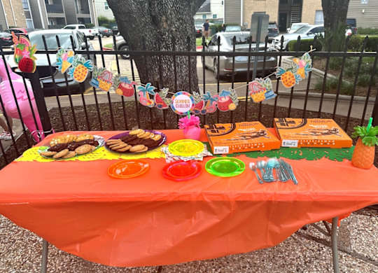 A table with an orange tablecloth is set up for an event.