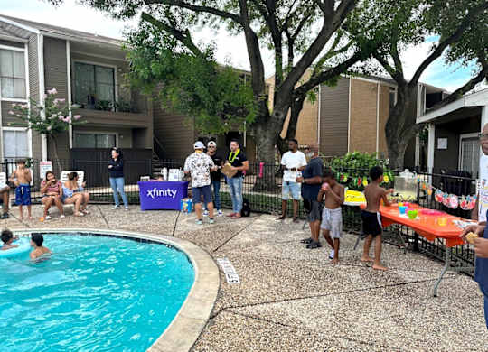 A group of people are gathered around a pool in a backyard.