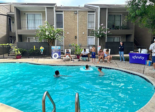 A group of people are gathered around a pool.