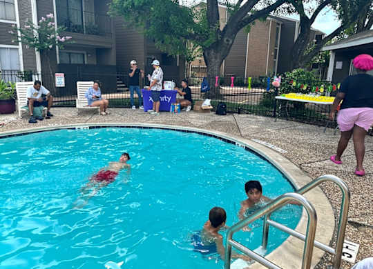 People are swimming in a pool with a blue tarp in the background.