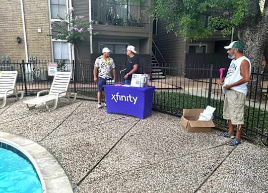 Three men are standing around a purple box labeled