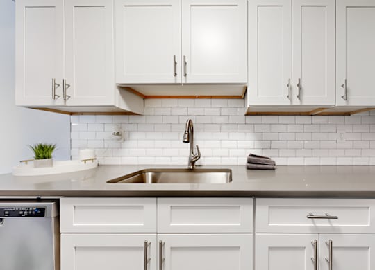 kitchen with tile backsplash, white cabinets, and stainless steel sink at Spring Lake Cove Apartments, Birmingham, 35215