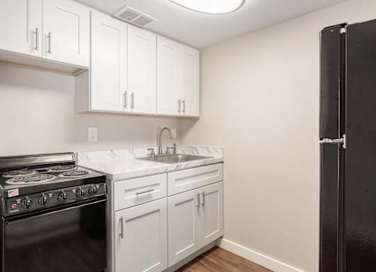 a Waterview Crossing Apartment kitchen with white cabinets and a black appliances