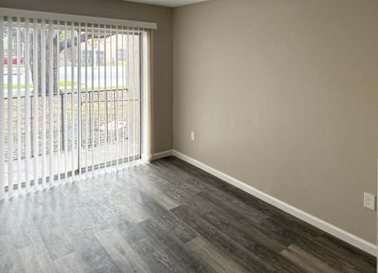 A room with a sliding glass door and wood-style flooring.