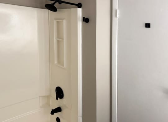 a renovated bathroom with a tub/shower with black hardware